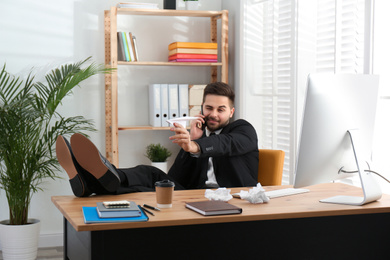 Photo of Lazy employee playing with paper plane at table in office