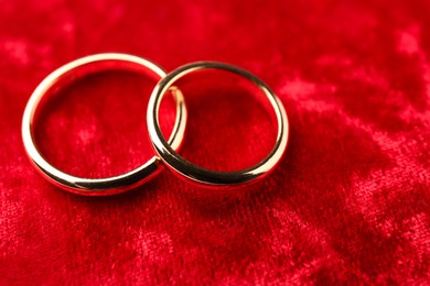 Honeymoon concept. Two golden rings on red velvet, closeup