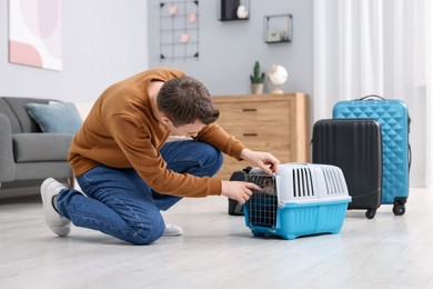 Photo of Travel with pet. Man closing carrier with cat at home