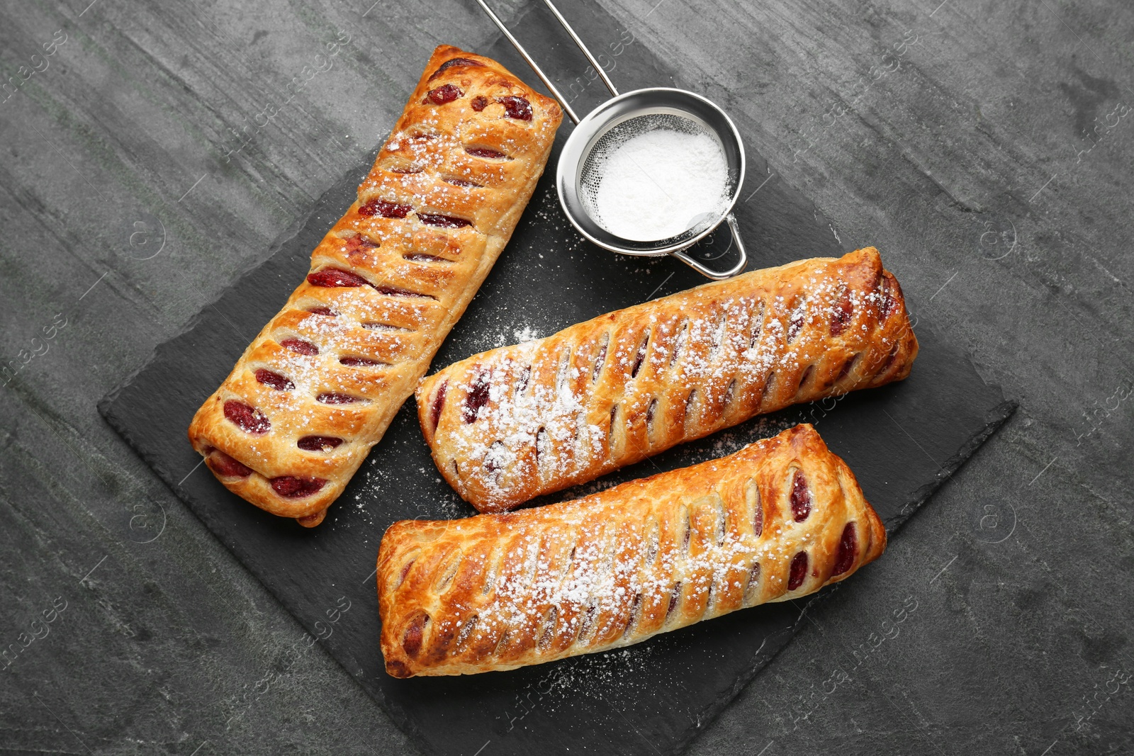 Photo of Fresh tasty puff pastry with sugar powder served on grey table, top view