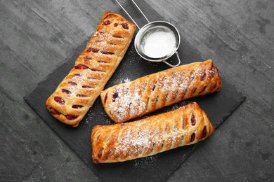 Photo of Fresh tasty puff pastry with sugar powder served on grey table, top view