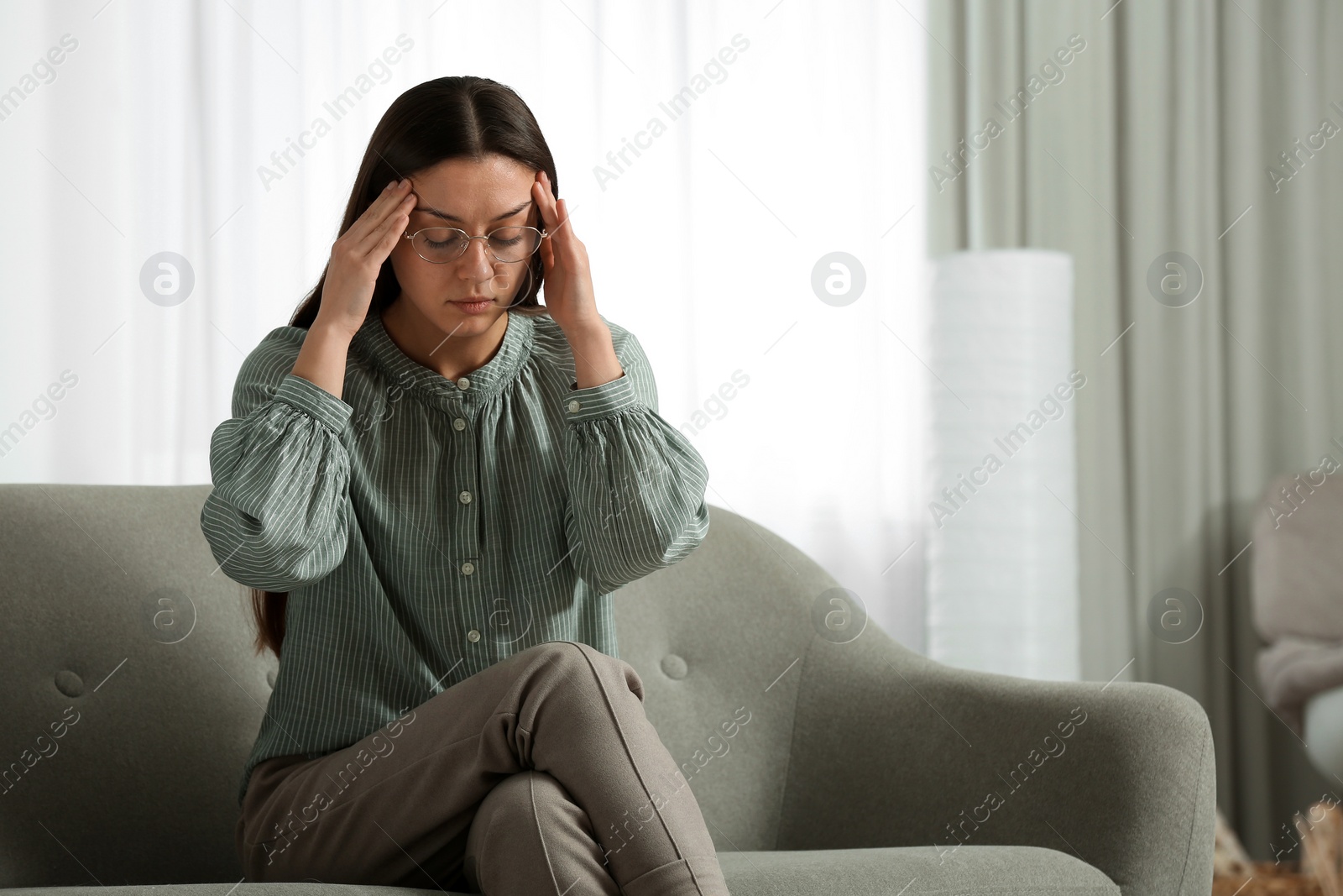 Photo of Stressed young woman on sofa at home. Space for text