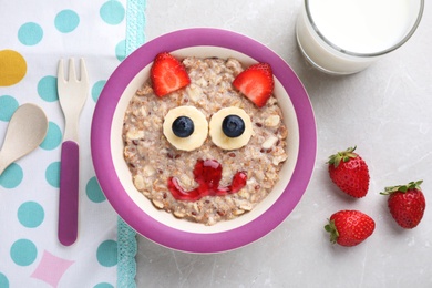 Photo of Tasty porridge served with berries, jam and milk on marble table, flat lay. Creative idea for kids breakfast