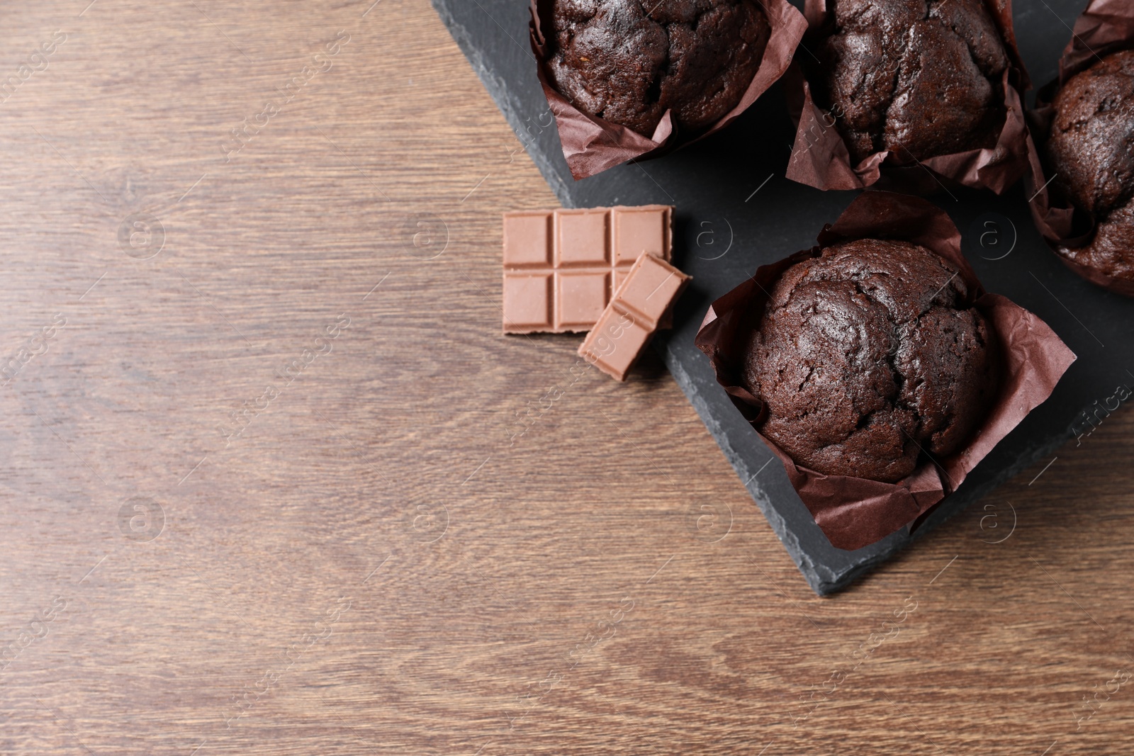 Photo of Tasty chocolate muffins on wooden table, top view. Space for text