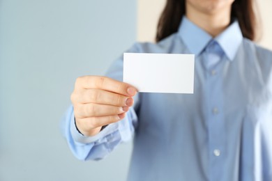 Woman holding blank business card on color background, closeup. Mockup for design