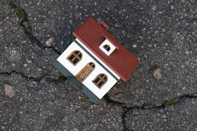 Photo of House model on cracked asphalt, top view. Earthquake disaster