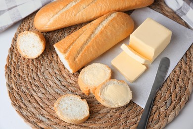 Photo of Tasty cut baguette with fresh butter on white table