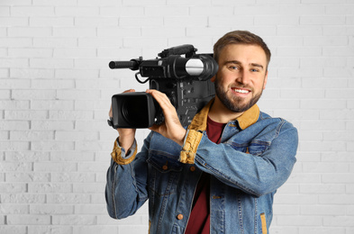 Photo of Operator with professional video camera near white brick wall