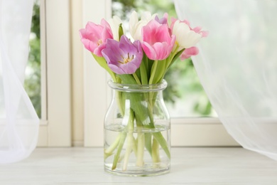 Photo of Beautiful fresh tulips on window sill indoors. Spring flowers