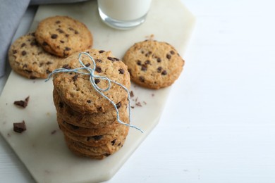 Photo of Tasty chocolate chip cookies on white wooden table, closeup. Space for text