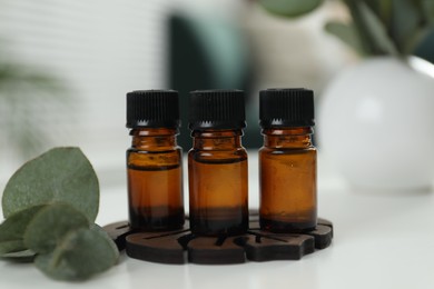 Aromatherapy. Bottles of essential oil and eucalyptus leaves on white table