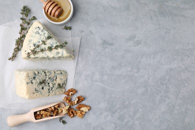 Tasty blue cheese with thyme, honey and walnuts on grey table, flat lay. Space for text