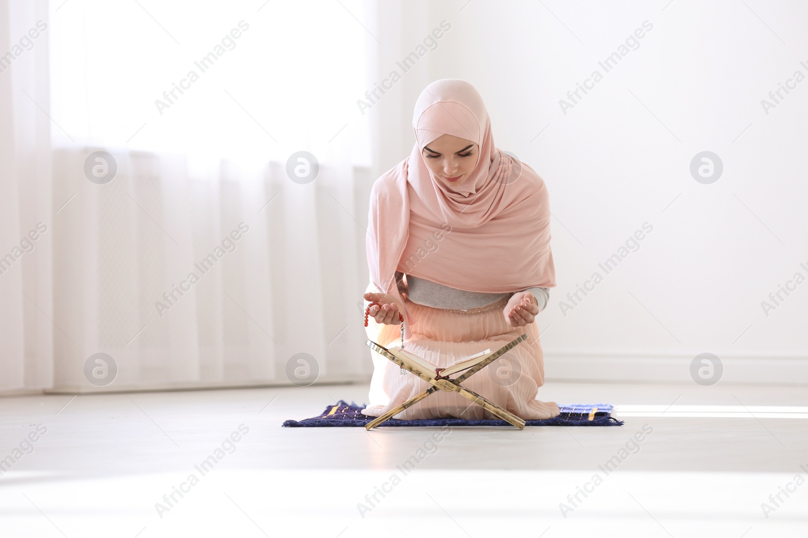 Photo of Muslim woman in hijab reading Koran indoors