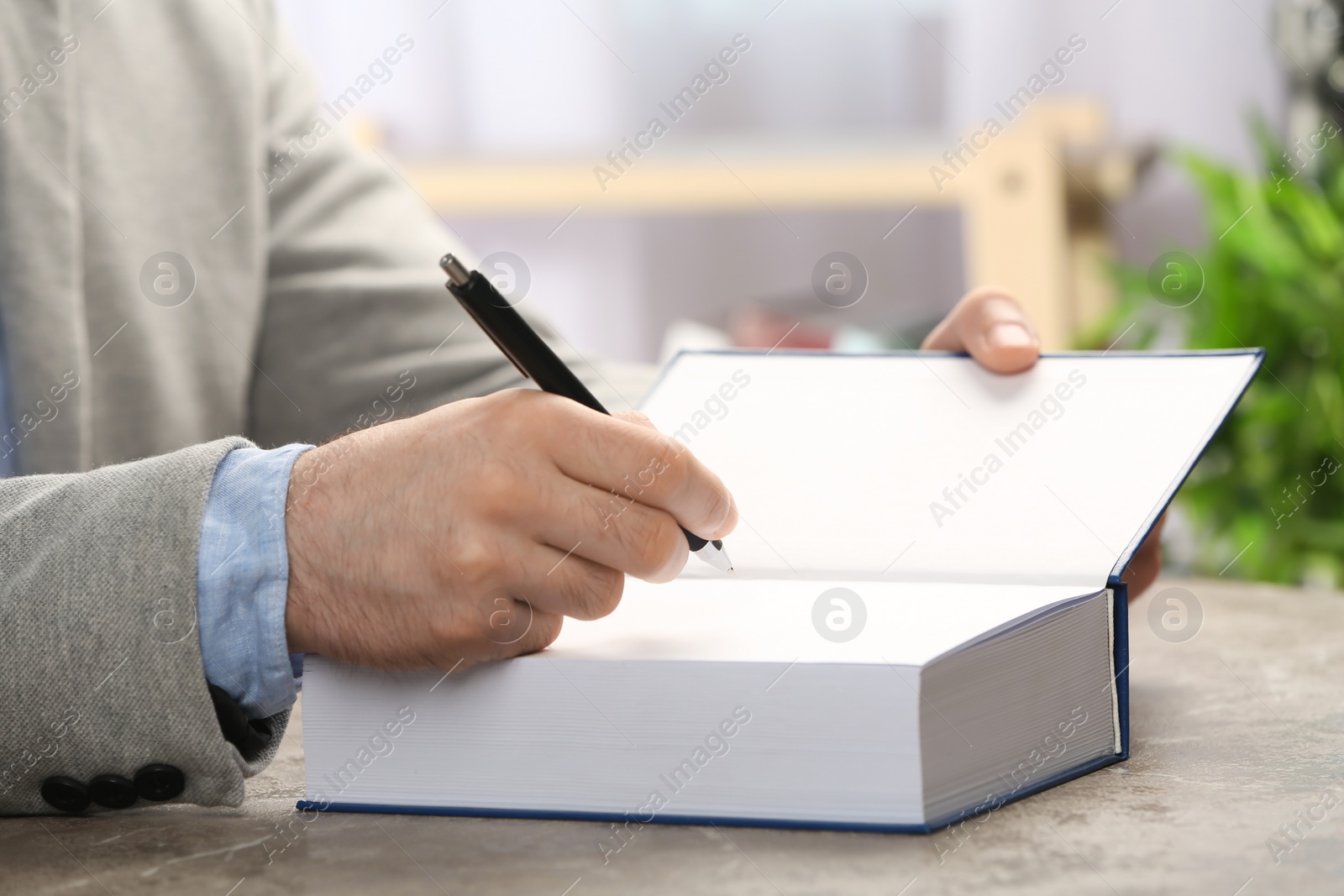 Photo of Writer signing autograph in book at table, closeup