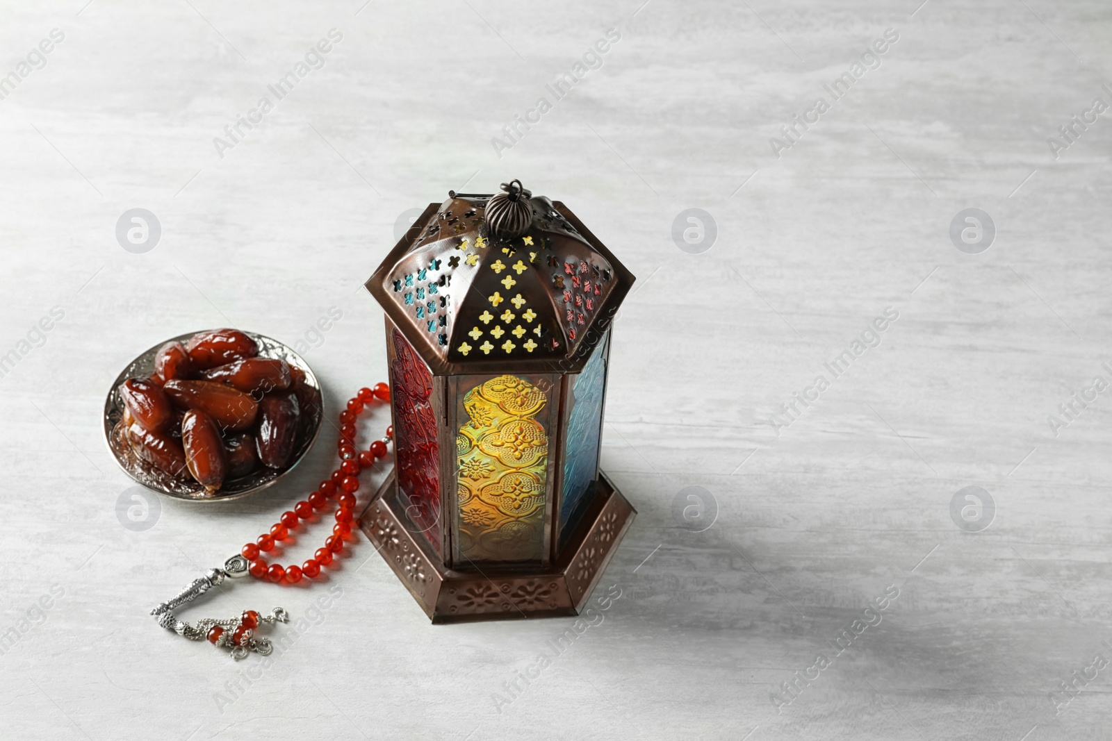 Photo of Muslim lamp, dates and misbaha on light background. Fanous as Ramadan symbol