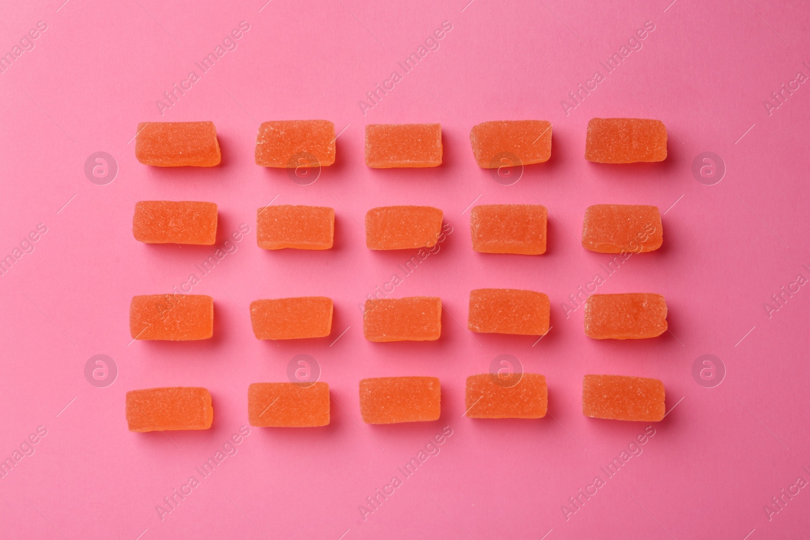 Photo of Tasty orange jelly candies on pink background, flat lay