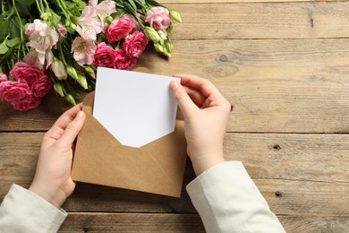 Photo of Happy Mother's Day. Woman holding envelope with blank card at wooden table, top view. Space for text