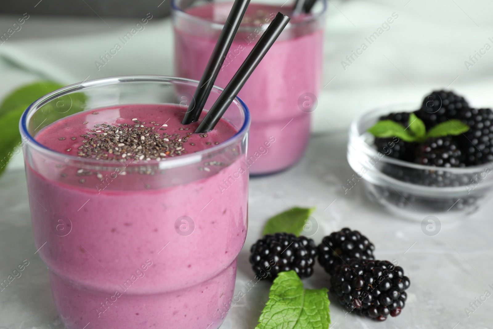 Photo of Delicious blackberry smoothie on marble table, closeup. Space for text