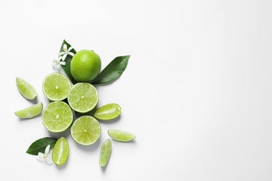 Photo of Limes, flowers and leaves on white background, top view. Citrus fruits