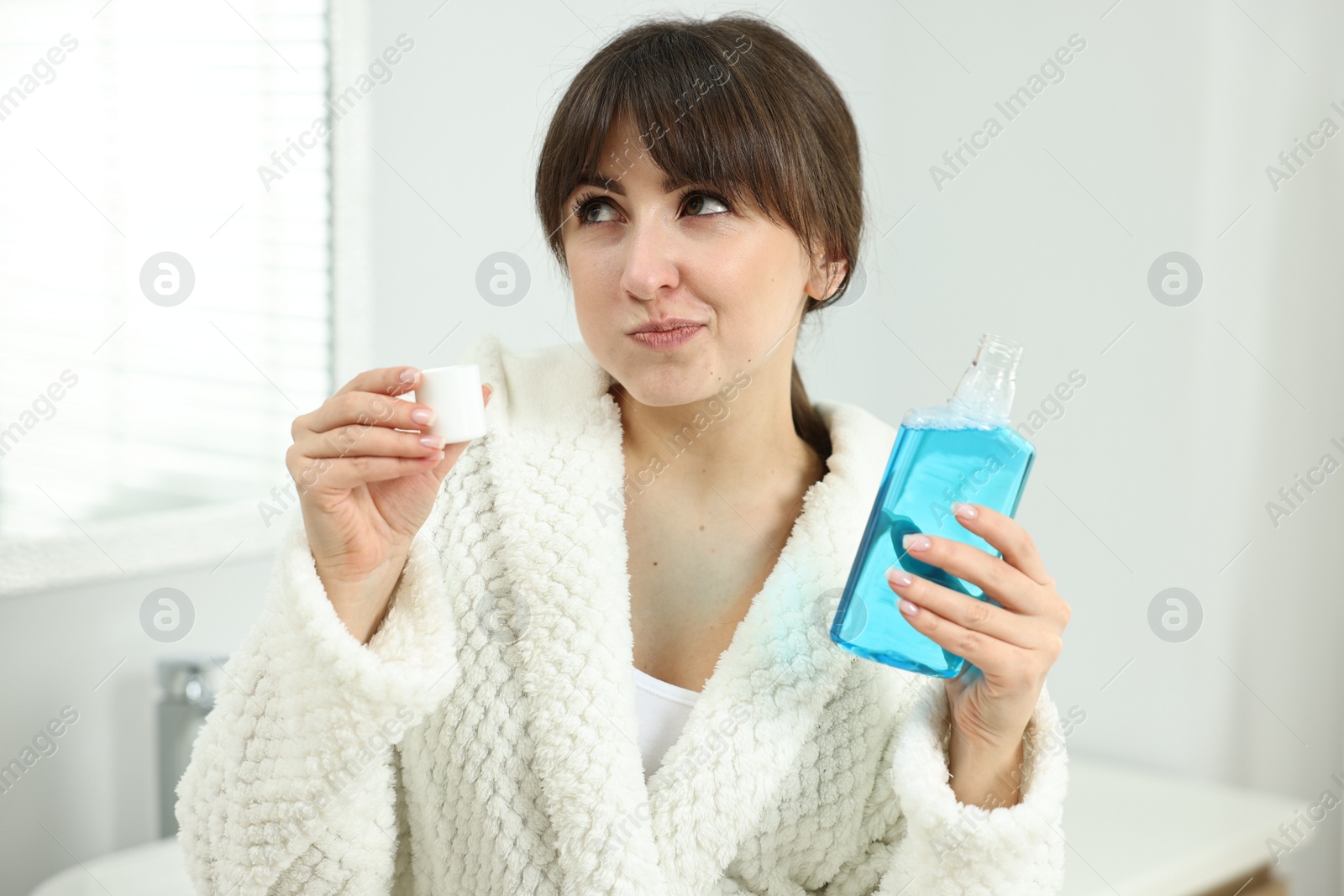 Photo of Young woman using mouthwash in bathroom. Oral hygiene