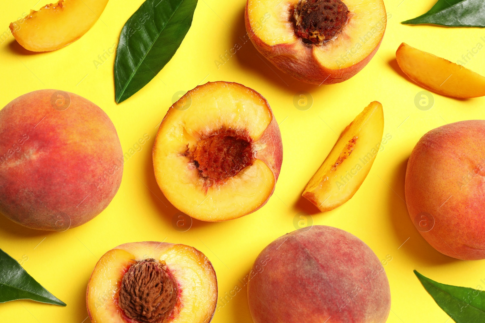 Photo of Delicious juicy peaches and green leaves on yellow background, flat lay