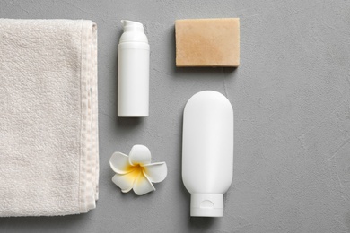 Photo of Flat lay composition with spa cosmetics and towel on grey background