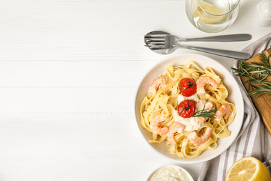 Delicious pasta with shrimps served on white wooden table, flat lay. Space for text