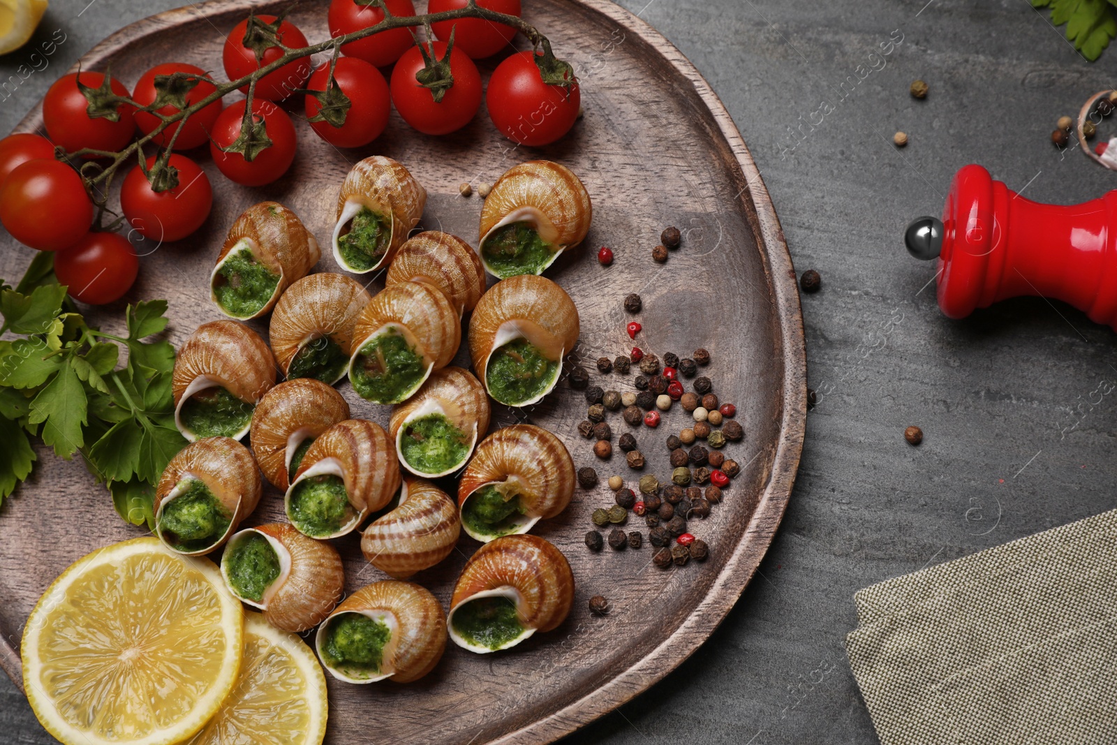 Photo of Delicious cooked snails served on grey table, flat lay