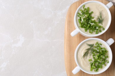 Photo of Bowls with tasty creamy soup of parsnip on light grey background, top view. Space for text