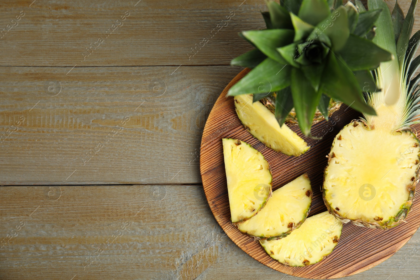 Photo of Whole and cut pineapples on wooden table, flat lay. Space for text