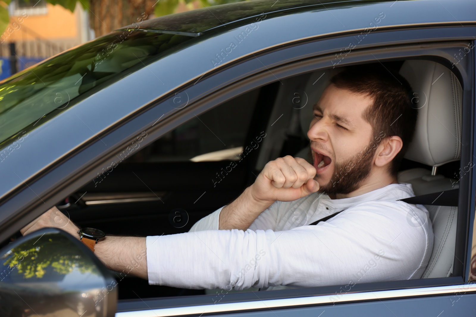 Photo of Tired man yawning in his modern car