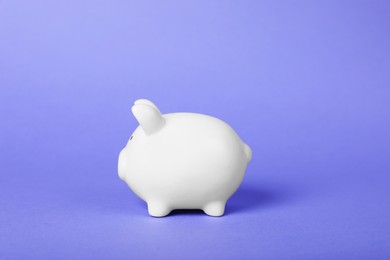 Photo of Ceramic piggy bank on purple background. Financial savings