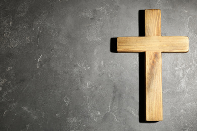 Photo of Wooden Christian cross on grey stone table, top view with space for text. Religion concept