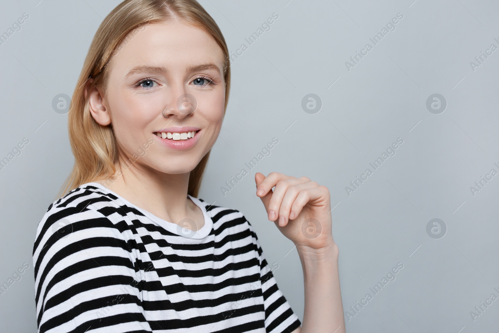 Photo of Portrait of beautiful young woman in striped t-shirt on grey background. Space for text