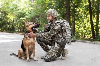 Photo of Man in military uniform with German shepherd dog outdoors