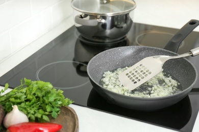 Photo of Frying chopped onion on cooktop in kitchen, closeup