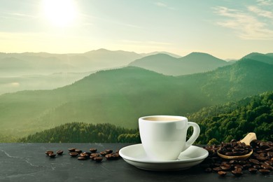 Cup of aromatic hot coffee on black table and beautiful view of mountain landscape. Space for text