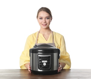 Portrait of young woman with modern multi cooker at table against white background