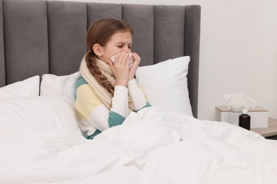 Sick girl with tissue coughing on bed at home