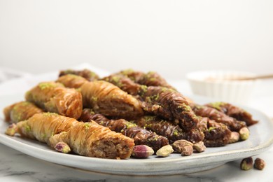 Photo of Delicious baklava with pistachio nuts on white marble table, closeup