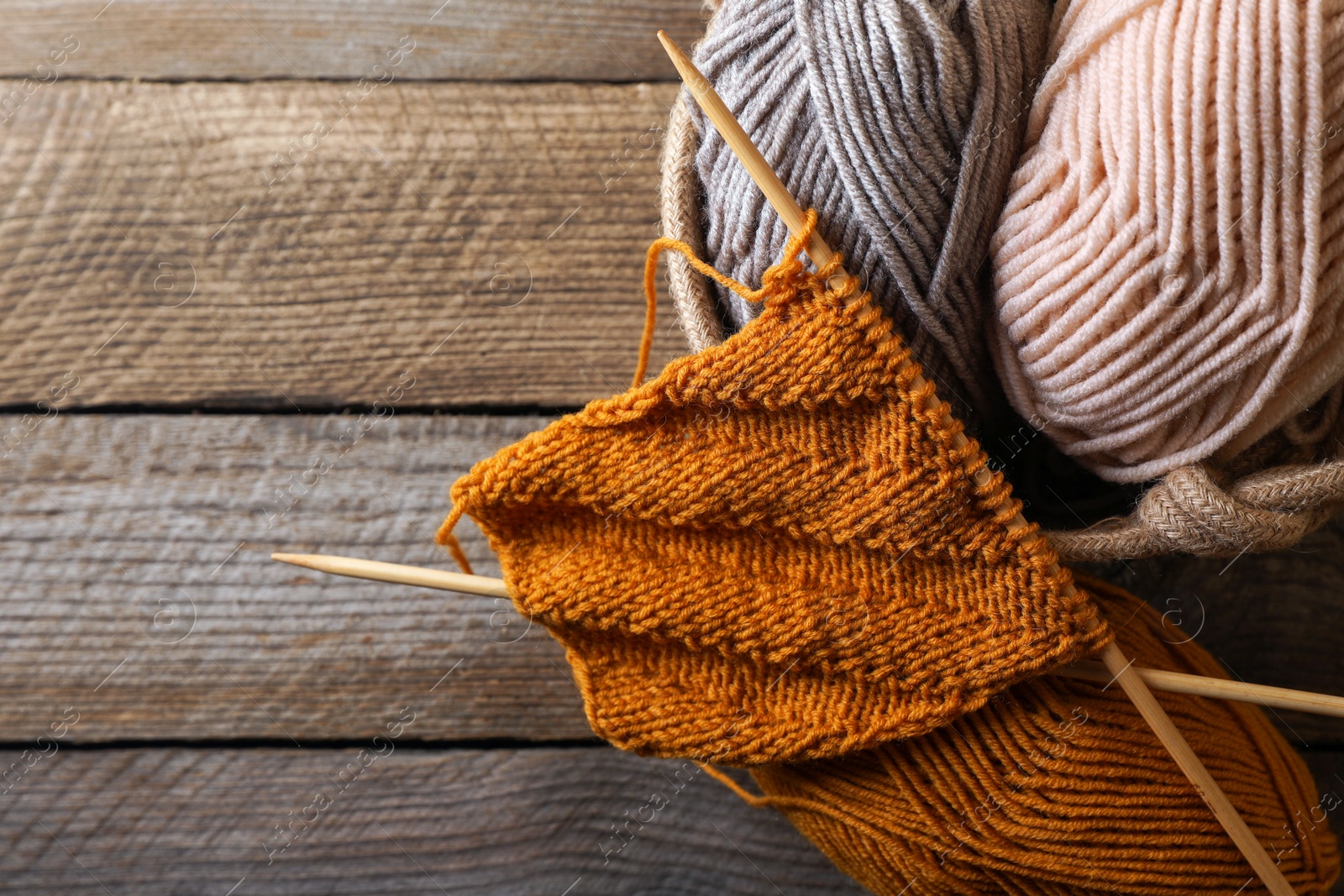 Photo of Soft colorful yarns, knitting and needles on wooden table, top view. Space for text