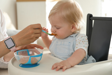 Photo of Mother feeding her cute little baby with healthy food at home