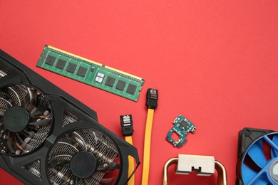 Photo of Graphics card and other computer hardware on red background, flat lay. Space for text