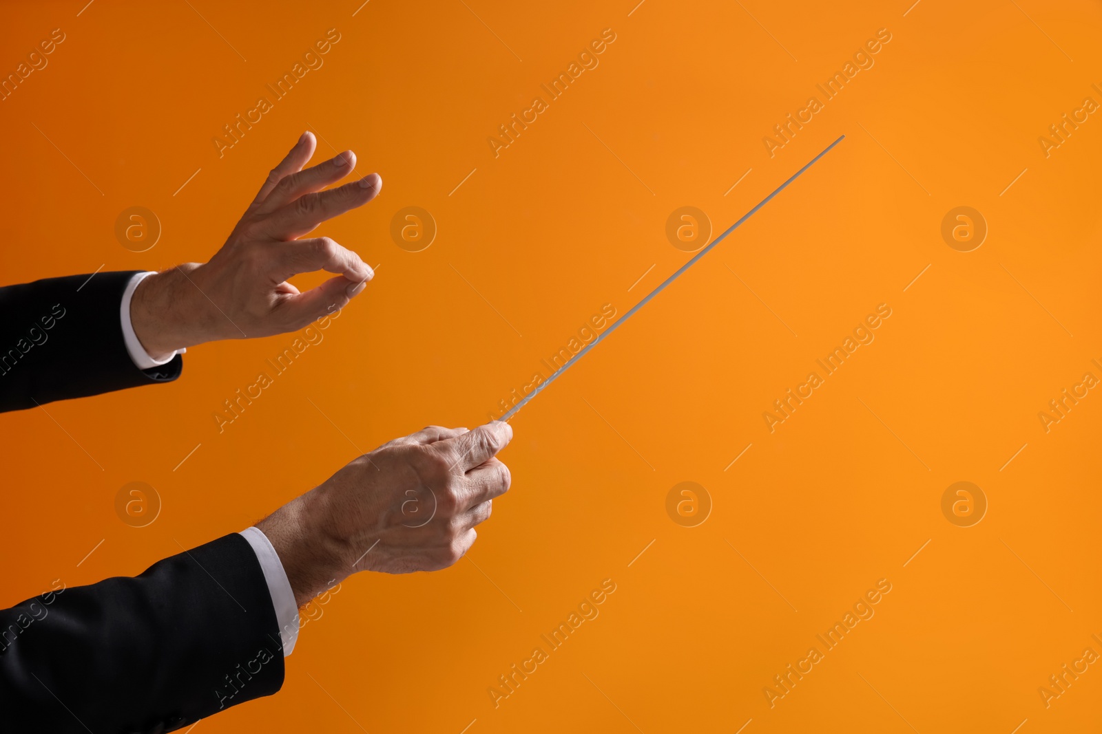 Photo of Professional conductor with baton on orange background, closeup. Space for text