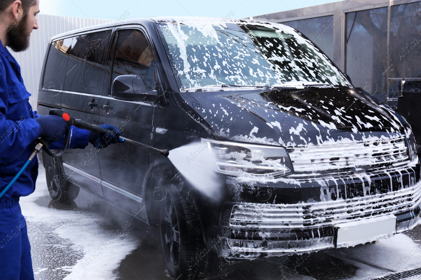 Photo of Worker cleaning automobile with high pressure water jet at car wash