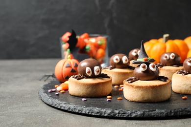 Photo of Delicious biscuits with chocolate spiders on grey table. Halloween celebration