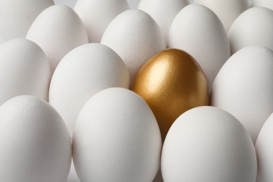 Photo of Golden egg among ordinary ones as background, closeup