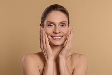 Photo of Woman massaging her face on beige background