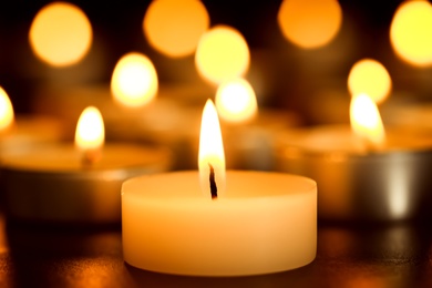 Photo of Burning candle on table, closeup. Funeral symbol