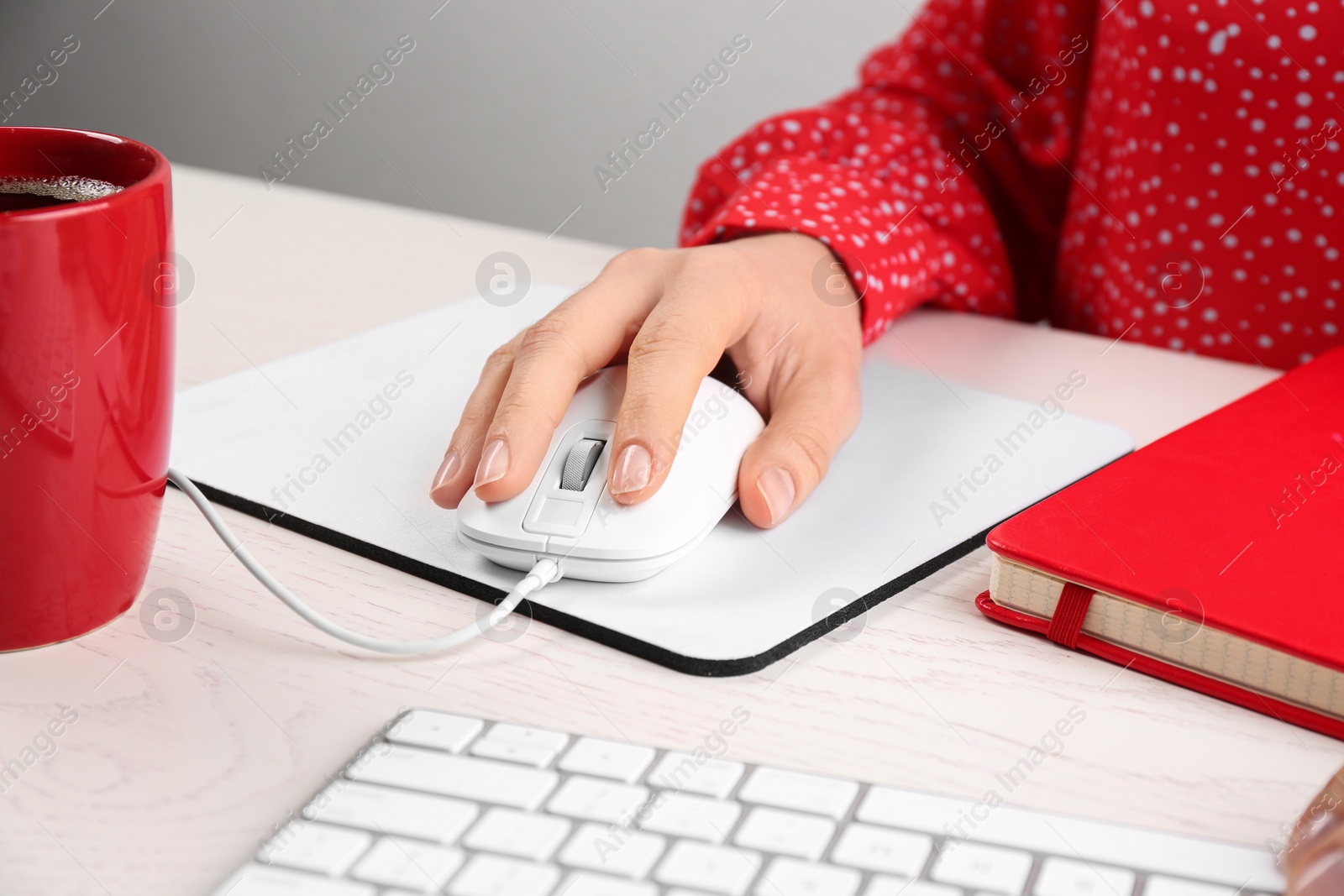 Photo of Woman using modern wired optical mouse at office table, closeup